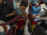 A health worker prepares a vaccine injection for a student on child immunization at SD Inpres Palupi, Palu City, Central Sulawesi Province,...