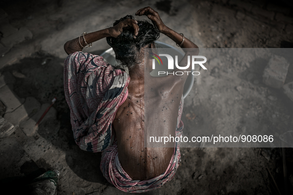 An old woman is washing hair and flies are all over her body at Dhapa west dumping ground, Kolkata, India. January 20, 2015.  *** Go to http...