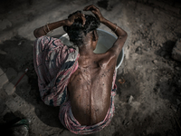 An old woman is washing hair and flies are all over her body at Dhapa west dumping ground, Kolkata, India. January 20, 2015.  *** Go to http...