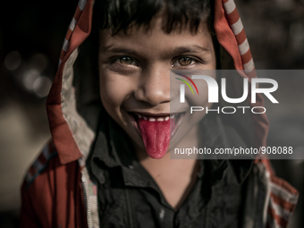 A kid is showing his red tongue at Dhapa west dumping ground, Kolkata, India. January 20, 2015.  *** Go to http://nurphoto.com/en/reportages...