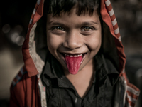 A kid is showing his red tongue at Dhapa west dumping ground, Kolkata, India. January 20, 2015.  *** Go to http://nurphoto.com/en/reportages...