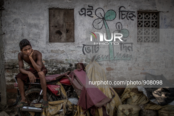 a boy is sitting in front of his house and there is a promotional symbol of election campaign. Dhapa, Kolkata, India. September 10, 2015.  *...