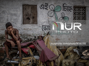 a boy is sitting in front of his house and there is a promotional symbol of election campaign. Dhapa, Kolkata, India. September 10, 2015.  *...