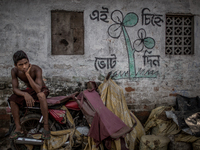 a boy is sitting in front of his house and there is a promotional symbol of election campaign. Dhapa, Kolkata, India. September 10, 2015.  *...