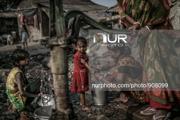 A woman is washing her daughter's hand and other is collecting water from a tube-well. Dhapa, Kolkata, India. January 20, 2015.  *** Go to h...