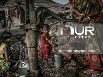 A woman is washing her daughter's hand and other is collecting water from a tube-well. Dhapa, Kolkata, India. January 20, 2015.  *** Go to h...