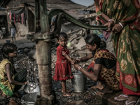 A woman is washing her daughter's hand and other is collecting water from a tube-well. Dhapa, Kolkata, India. January 20, 2015.  *** Go to h...