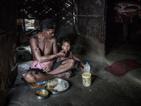 A guard of waste dumping ground is feeding his grand son during lunch time. Dhapa, Kolkata, India. September 17, 2015.  *** Go to http://nur...