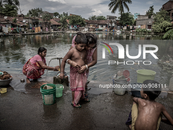 A mother is tying gamcha to her kid. Dhapa, Kolkata, India. September 14, 2015.  *** Go to http://nurphoto.com/en/reportages/51754 to see mo...