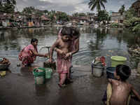 A mother is tying gamcha to her kid. Dhapa, Kolkata, India. September 14, 2015.  *** Go to http://nurphoto.com/en/reportages/51754 to see mo...