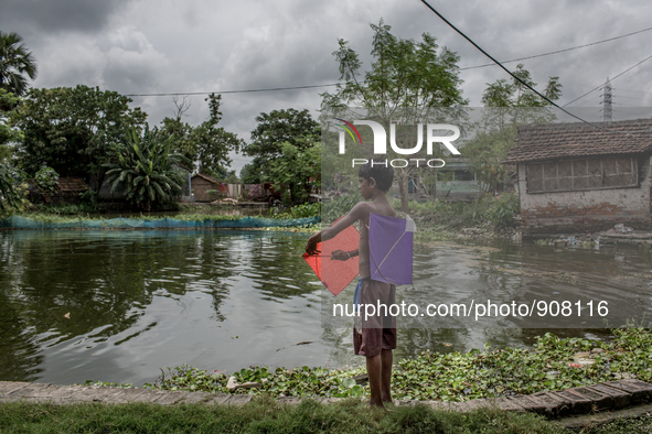 A kid is preparing his kites. Dhapa, Kolkata, India. September 11, 2015.  *** Go to http://nurphoto.com/en/reportages/51754 to see more ****...