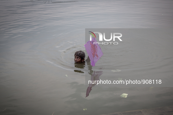 A kid is saving his kite from the water. Dhapa, Kolkata, India. September 18, 2015.  *** Go to http://nurphoto.com/en/reportages/51754 to se...