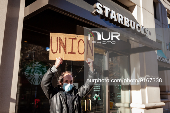 Samuel Dukore holds a "union" sign overhead as he celebrates employees' vote to join Starbucks Workers United, by a 4 to 1 margin.  Dukore h...