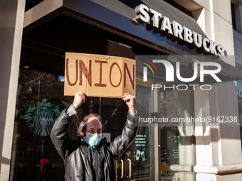 Samuel Dukore holds a "union" sign overhead as he celebrates employees' vote to join Starbucks Workers United, by a 4 to 1 margin.  Dukore h...