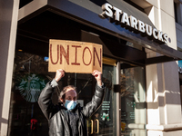 Samuel Dukore holds a "union" sign overhead as he celebrates employees' vote to join Starbucks Workers United, by a 4 to 1 margin.  Dukore h...