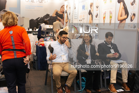 fairgoers are seen trying out a massage device during the opening day of Medica 2022, a medical technology and health care exhibition in Due...