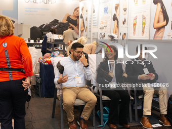 fairgoers are seen trying out a massage device during the opening day of Medica 2022, a medical technology and health care exhibition in Due...