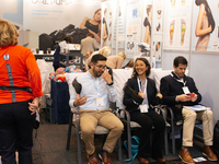 fairgoers are seen trying out a massage device during the opening day of Medica 2022, a medical technology and health care exhibition in Due...