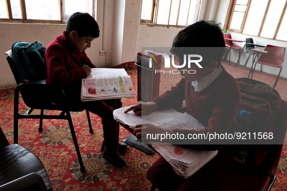 Students read inside a class room as heating facilities are installed in a private school in Baramulla Jammu and Kashmir India on 18 Novembe...