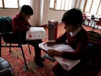 Students read inside a class room as heating facilities are installed in a private school in Baramulla Jammu and Kashmir India on 18 Novembe...