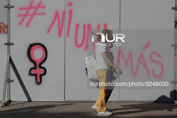 A woman walks past slogans on metal fences in Mexico City's Zócalo to mark the International Day for the Elimination of Violence against Wom...