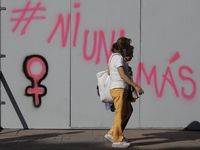 A woman walks past slogans on metal fences in Mexico City's Zócalo to mark the International Day for the Elimination of Violence against Wom...