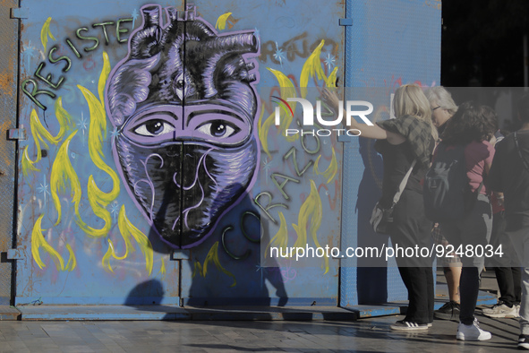 Two women look at a mural on metal fences in Mexico City's Zócalo to mark the International Day for the Elimination of Violence against Wome...