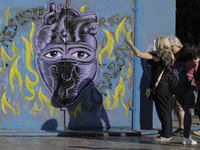 Two women look at a mural on metal fences in Mexico City's Zócalo to mark the International Day for the Elimination of Violence against Wome...