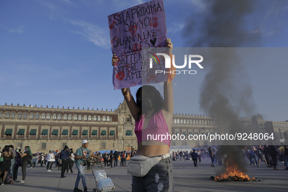 A member of the feminist Black Bloc holds a banner while other women burn posters in Mexico City's Zócalo to mark the International Day for...