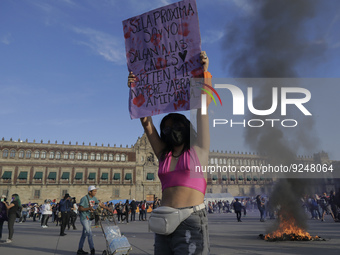 A member of the feminist Black Bloc holds a banner while other women burn posters in Mexico City's Zócalo to mark the International Day for...