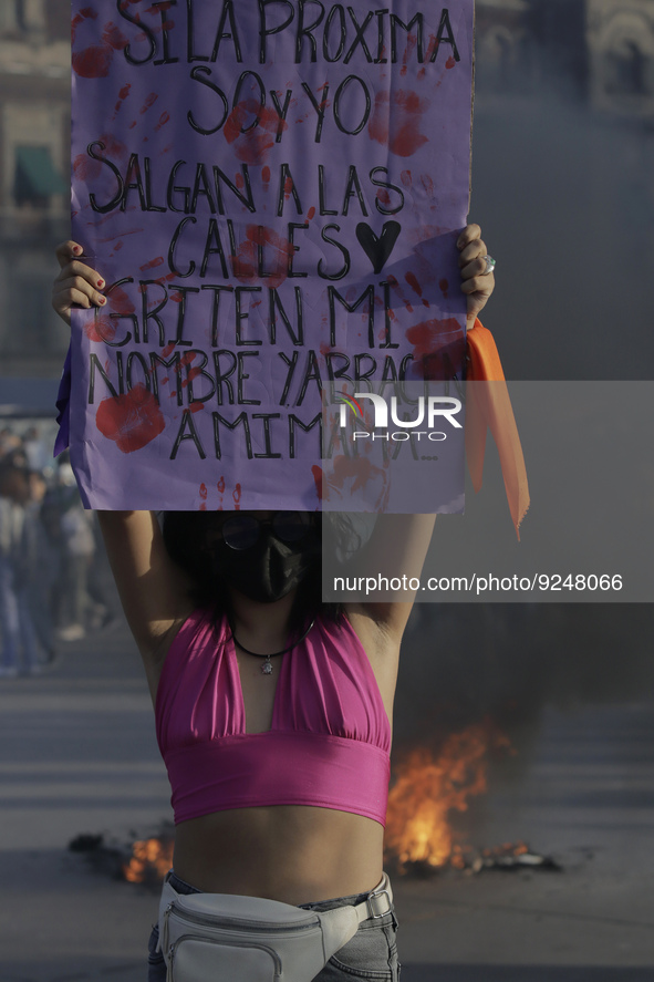 A member of the feminist Black Bloc holds a banner while other women burn posters in Mexico City's Zócalo to mark the International Day for...