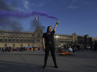 A member of the feminist Black Bloc burns a flare in the Zócalo in Mexico City to mark the International Day for the Elimination of Violence...