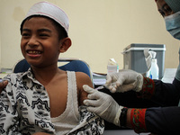 A Health workers inject students with the Diphtheria and Tetanus vaccines during child immunization at an elementary school in Lhokseumawe C...