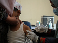 A Health workers inject students with the Diphtheria and Tetanus vaccines during child immunization at an elementary school in Lhokseumawe C...