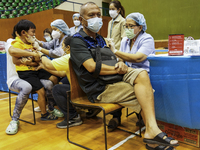 People receive doses of the Pfizer COVID-19 vaccine booster at a vaccination center inside a stadium in Bangkok, Thailand, 03 December 2022....