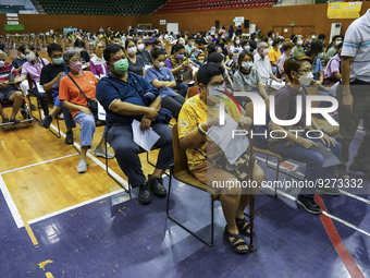 People sit and wait up to receive the COVID-19 vaccine booster vaccine at a vaccination center inside a stadium in Bangkok, Thailand, 03 Dec...