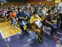 People sit and wait up to receive the COVID-19 vaccine booster vaccine at a vaccination center inside a stadium in Bangkok, Thailand, 03 Dec...