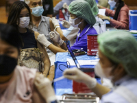 People receive doses of the Pfizer COVID-19 vaccine booster at a vaccination center inside a stadium in Bangkok, Thailand, 03 December 2022....