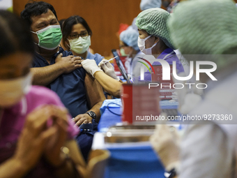 People receive doses of the Pfizer COVID-19 vaccine booster at a vaccination center inside a stadium in Bangkok, Thailand, 03 December 2022....