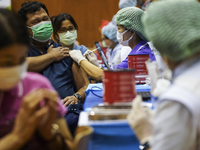 People receive doses of the Pfizer COVID-19 vaccine booster at a vaccination center inside a stadium in Bangkok, Thailand, 03 December 2022....