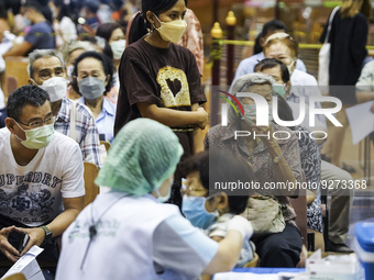 People sit and wait up to receive the COVID-19 vaccine booster vaccine at a vaccination center inside a stadium in Bangkok, Thailand, 03 Dec...