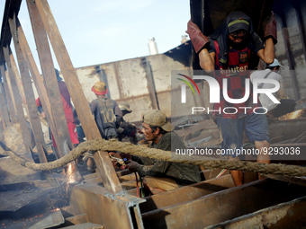 Myanmar workers work at a ship demolition site near Dala jetty in Yangon on December 7, 2022. (