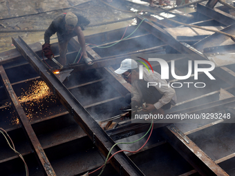 Myanmar workers work at a ship demolition site near Dala jetty in Yangon on December 7, 2022. (