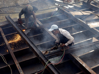 Myanmar workers work at a ship demolition site near Dala jetty in Yangon on December 7, 2022. (