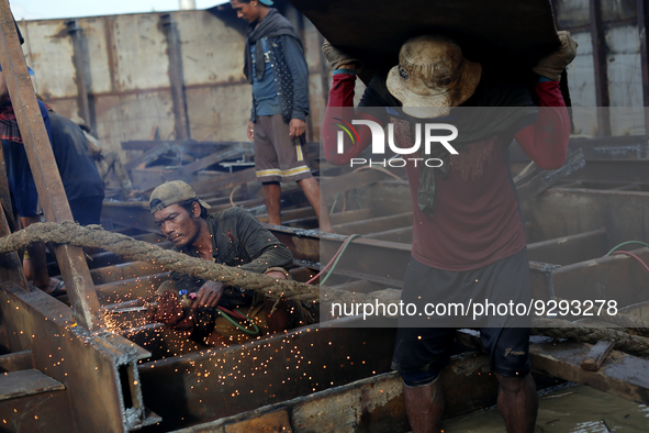 Myanmar workers work at a ship demolition site near Dala jetty in Yangon on December 7, 2022. 