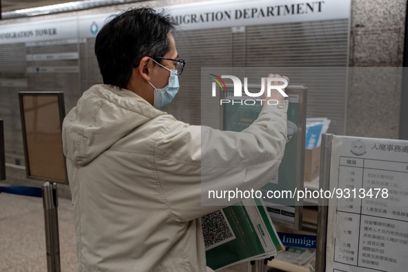 A worker removing paper with Leave Home Safe QR Code printed on them at a government office building on December 13, 2022 in Hong Kong, Chin...