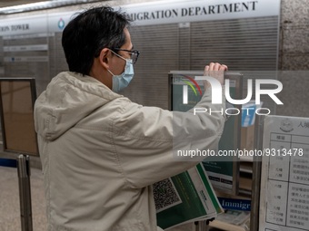 A worker removing paper with Leave Home Safe QR Code printed on them at a government office building on December 13, 2022 in Hong Kong, Chin...