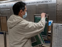 A worker removing paper with Leave Home Safe QR Code printed on them at a government office building on December 13, 2022 in Hong Kong, Chin...