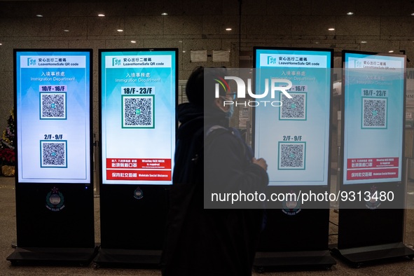 A women walks pass monitor displaying Leave Home Safe QR Code on December 13, 2022 in Hong Kong, China. The Hong Kong Government announced t...