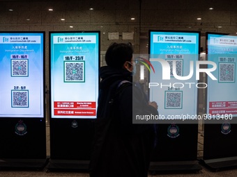 A women walks pass monitor displaying Leave Home Safe QR Code on December 13, 2022 in Hong Kong, China. The Hong Kong Government announced t...